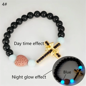Détail du bracelet tressé avec pendentif croix et perles lumineuses montrant l'effet de nuit