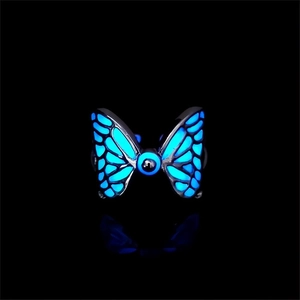 Detailed close-up of luminous butterfly ring with blue glow effect on black background