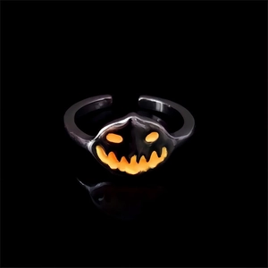 Macro view of glowing pumpkin face ring with glowing orange light on black background