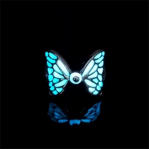 Luminous blue butterfly ring with glowing eye detail and black metal base on dark background