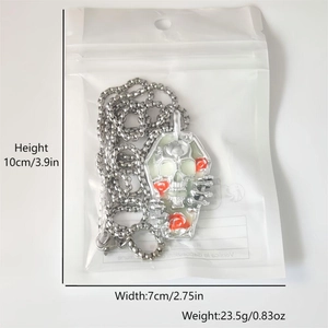 Detailed view of skull and red roses inside a coffin pendant in original packaging