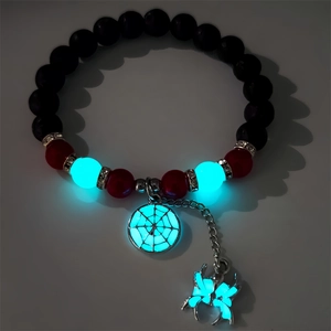 Glow-in-the-dark Halloween spider web bead bracelet with luminous charms in dark setting
