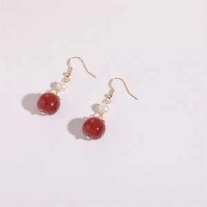 Détail des boucles d'oreilles dorées 14K avec perles d'agate rouge et perles d'eau douce