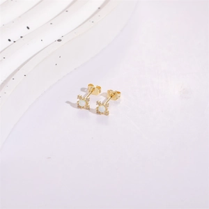 Detail of star-shaped opal stud earrings with gold plating and zircon accents on stone