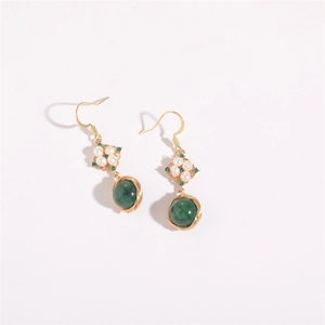 Close-up of gold wire wrapped earrings with freshwater pearls and green stones