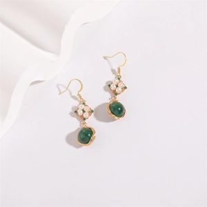 Detail of vintage gold pearl earrings with green gemstones and woven wire accents