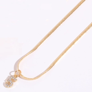 Dettaglio di una collana a catena serpente dorata con ciondolo numero cinque in zirconi