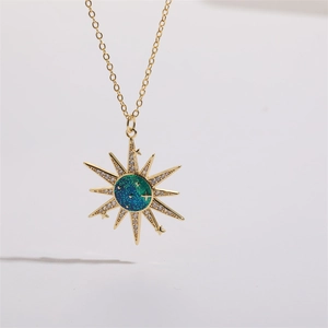 Close-up of golden sunburst pendant with blue-green enamel and sparkling zircon accents
