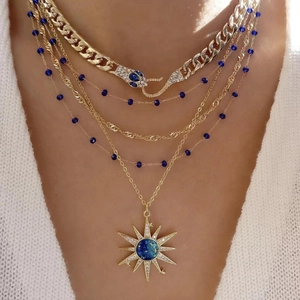 Layered gold starburst necklace set with blue enamel sun pendant and snake chain detail