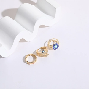 Trois bagues œil porte-bonheur dorées avec émail bleu et zircon sur fond en marbre blanc