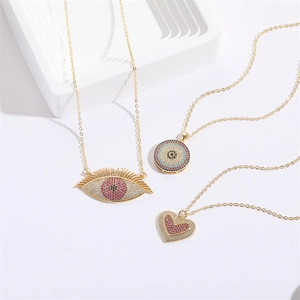 Detailed view of evil eye and heart pendants with colorful pavé crystals on gold chains