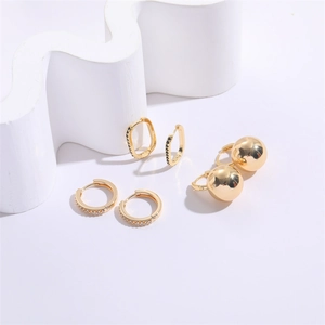 Detail of geometric U-shaped gold earrings with white and black zircon and polished beads