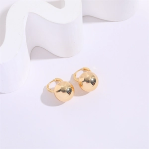Detailed macro view of polished gold geometric U-shaped sphere hoop earrings on white props