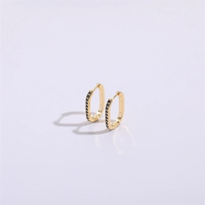 Detailed view of U-shaped gold earrings with black zircon stones on a purple background