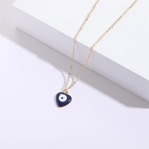 Collier cœur doré avec pendentif œil bleu en émail sur un support géométrique blanc