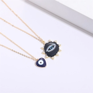 Vue détaillée du pendentif cœur mauvais œil et du collier de perles dorées