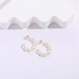 Elegant C-shaped pearl earrings with gold pins and white pearls on minimalist background