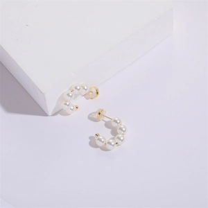 Elegant C-shaped pearl hoop earrings with gold metal accents and silicone backs