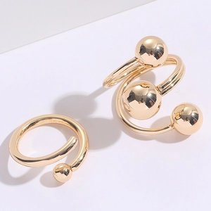 Dettaglio macro di orecchini a spirale dorati con sfere metalliche lucide e finitura liscia