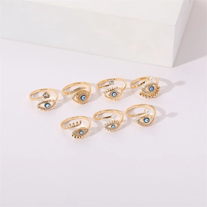 Detailed close-up of golden evil eye rings with blue zircon and pearls on white stone