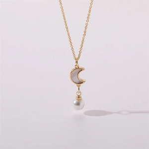 Macro shot of gold necklace featuring a shell moon pendant and round white pearl drop