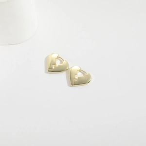 Detail of gold-plated broken heart earrings with textured puzzle edges and glossy finish