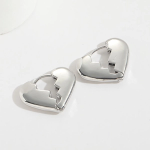 Detailed close-up of broken heart shaped silver earrings with a smooth polished finish