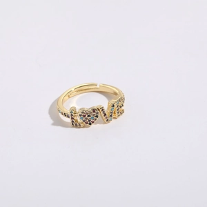 Gros plan d'une bague ajustable dorée à l'or 14K avec zircons colorés formant le mot LOVE