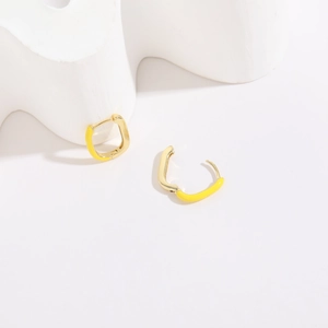 Detailed macro view of French U-shaped oval gold plated earrings with bright yellow enamel