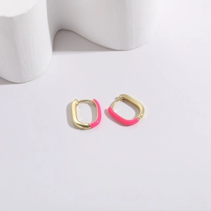 Macro detail of U-shaped gold earrings with bright magenta enamel on white geometric stand
