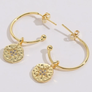 Close-up of 14K gold plated hoop earrings with starburst coin pendant and zircon stones