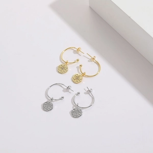 Close-up of gold and silver hexagram star earrings with zircon inlay on white blocks