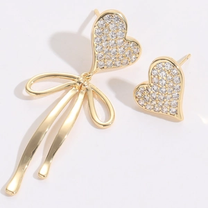 Detail of 14K gold plated asymmetric heart earrings with ribbons and sparkling zircon