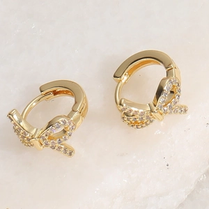 Macro view of gold bow-shaped earrings with micro-pave white zircon inlay details
