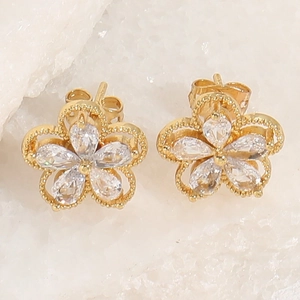 Detail view of 14K gold plated floral stud earrings with geometric cubic zirconia petals