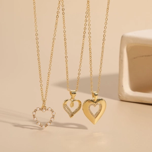 Detailed view of three 14K gold-plated heart pendants with pearls and zircons