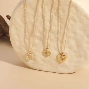 Three-piece gold plated heart necklace set featuring pearls and zircon on textured board