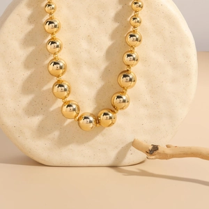 Detailed view of large golden beads with a high-polished mirror finish on a chic necklace