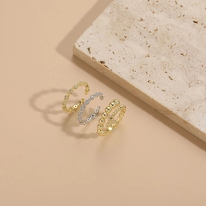 Detail view of gold and silver beaded rings with zircon insets on textured stone