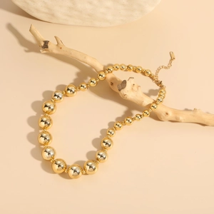 Detail of 18K gold-plated beaded necklace with gradient spheres on a natural branch