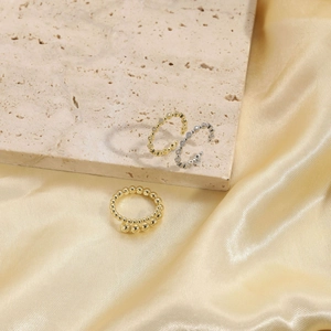 Detailed view of layered 14K gold plated beaded and zircon rings on elegant silk fabric