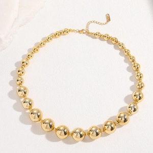 Minimalist 18K gold plated beaded necklace with graduated spheres on white stone surface