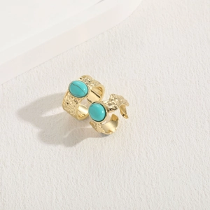 Detail of two gold-hammered rings with oval turquoise stones in bohemian style