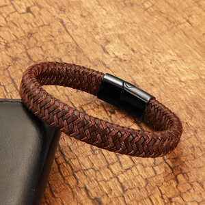 Detail view of brown braided leather bracelet with black magnetic clasp on wooden background