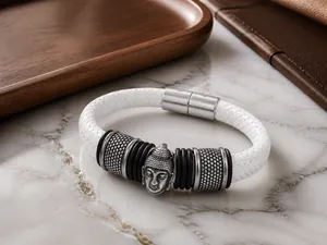 Dettaglio del ciondolo testa di Buddha su bracciale in pelle intrecciata bianca con chiusura inox