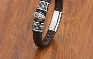 Dettaglio di un bracciale in pelle intrecciata marrone da uomo con ciondolo a forma di Buddha