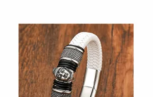 Dettaglio macro del ciondolo testa di Buddha su un bracciale in pelle intrecciata bianca