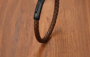 Dettaglio macro del cinturino in pelle marrone intrecciata e chiusura magnetica in metallo nero