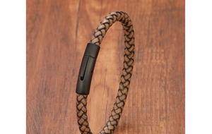 Dettaglio macro del bracciale in pelle intrecciata kaki con fibbia industriale nera opaca
