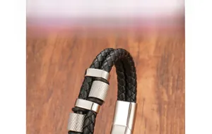 Detail of black woven leather men's bracelet with polished stainless steel clasp and knurled rings